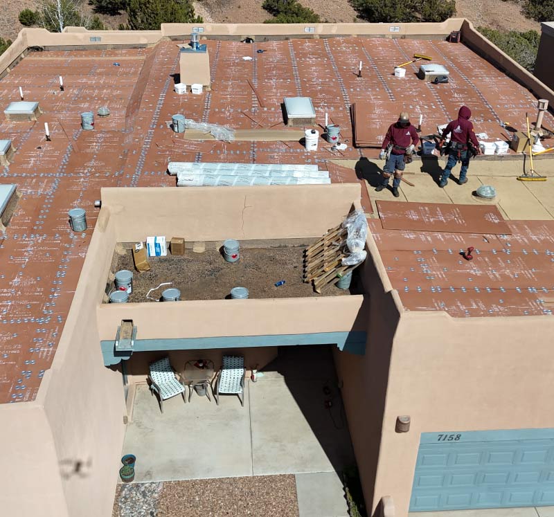 Roof Inspection 1 Aerial view of a TPO flat roof installation on an adobe-style home in Santa Fe, NM
